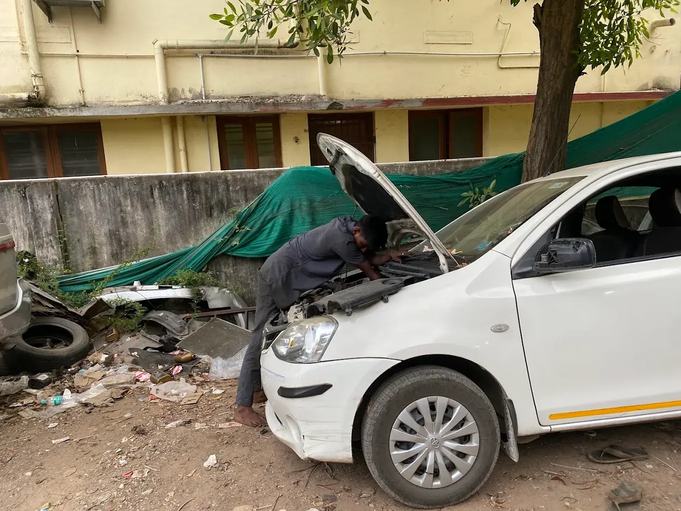 Technician checking the engine bay of a white Toyota Etios